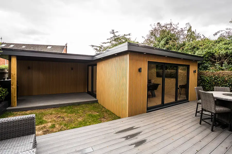 Large cedar garden annexe with decking at dusk